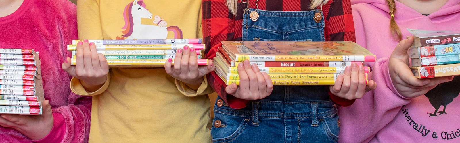 Children holding stacks of books
